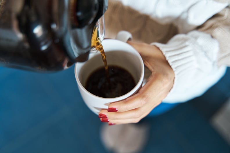 Close-up of a woman pouring herself hot coffee into a mug while staying at home.