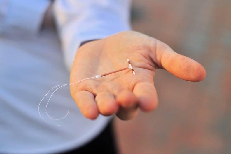 Woman holding an IUD birth control copper coil device in hand, example of a LARC (long-acting reversible contraception).