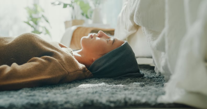 Closeup of woman sick with cancer lying on the floor with her eyes closed, enjoying a moment of relaxation in a sunlit room at home. 