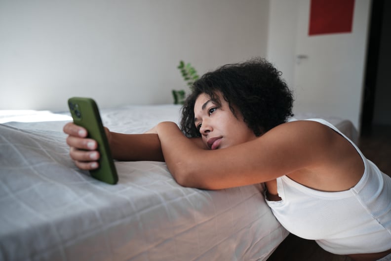 Upset African American woman looking at smartphone screen feeling sad reading sms message scrolling on social media